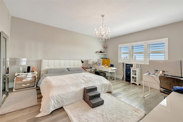 bedroom featuring wood finished floors, a desk, a chandelier, and baseboards