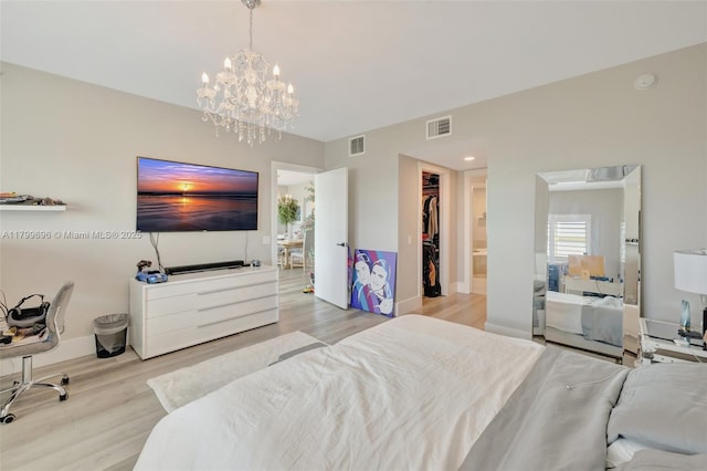 bedroom featuring wood finished floors, a chandelier, a spacious closet, baseboards, and a closet