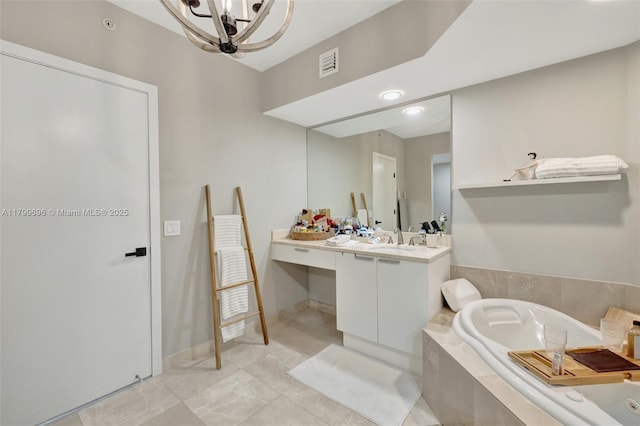 bathroom with a tub with jets, vanity, tile patterned floors, and a chandelier