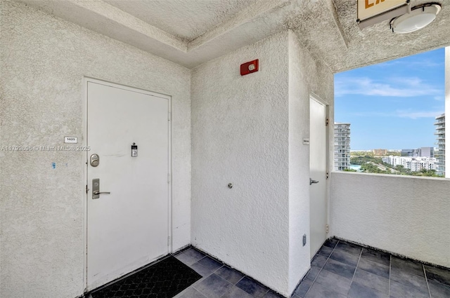 view of exterior entry with stucco siding, a balcony, and a view of city