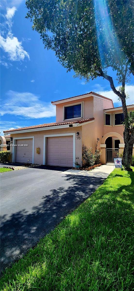 16624 Greens Edge Cir Unit 75, Weston, FL 33326 - view of front of home featuring stucco siding, a tiled roof, driveway, and an attached garage