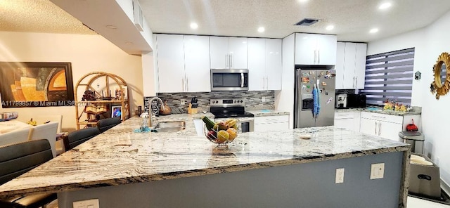 16624 Greens Edge Cir Unit 75, Weston, FL 33326 - kitchen with stainless steel appliances, a peninsula, a sink, backsplash, and a kitchen breakfast bar