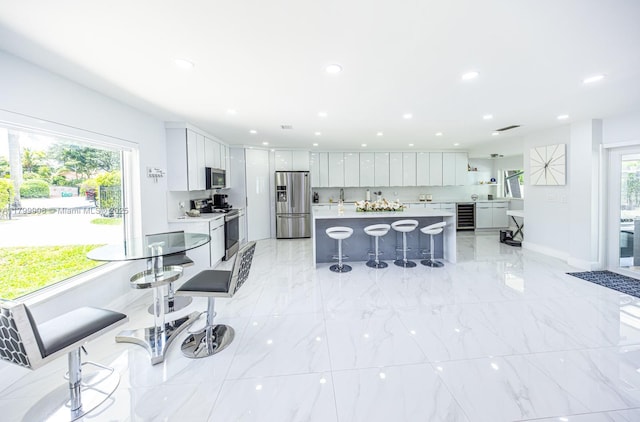 7345 N Oakmont Dr, Hialeah, FL 33015 - kitchen with appliances with stainless steel finishes, wine cooler, light countertops, a kitchen breakfast bar, and white cabinets