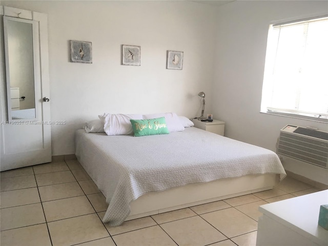 bedroom with light tile patterned flooring, an AC wall unit, and baseboards