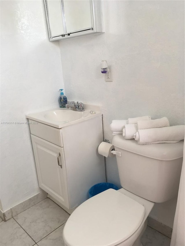 bathroom with toilet, vanity, and baseboards