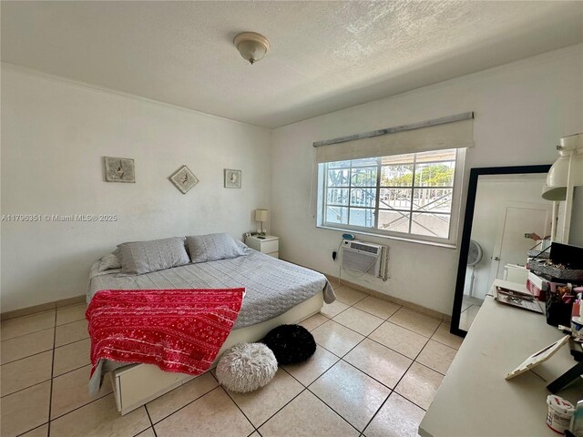 7435 Harding Ave Unit 101, Miami Beach, FL 33141 - bedroom with a wall unit AC, light tile patterned flooring, a textured ceiling, and baseboards