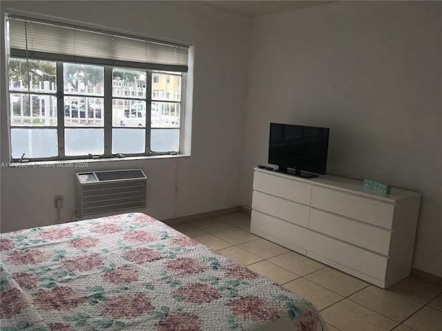 bedroom with light tile patterned flooring, baseboards, and a wall mounted AC