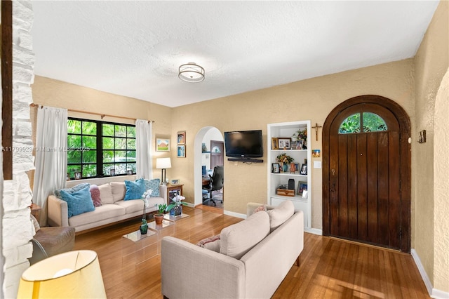 425 Cadagua Ave, Coral Gables, FL 33146 - living area featuring arched walkways, wood finished floors, a textured wall, baseboards, and a textured ceiling