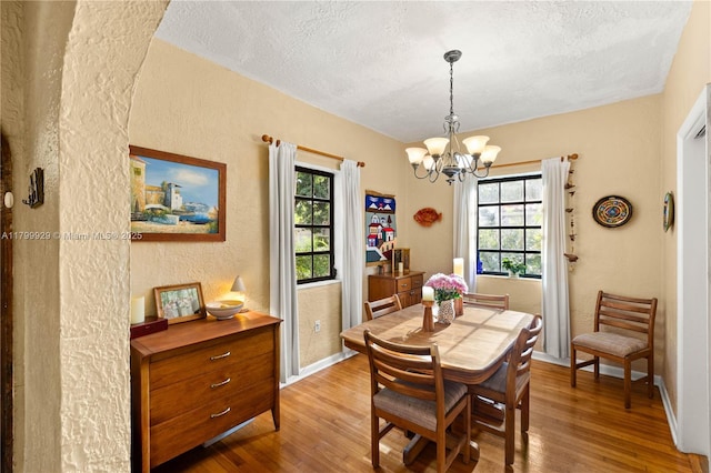 425 Cadagua Ave, Coral Gables, FL 33146 - dining room featuring a textured wall, wood finished floors, a textured ceiling, a chandelier, and baseboards