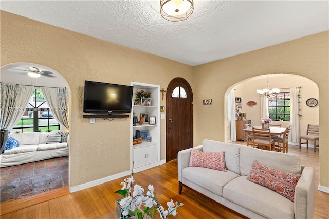 425 Cadagua Ave, Coral Gables, FL 33146 - living room featuring arched walkways, a textured wall, a chandelier, hardwood / wood-style flooring, and healthy amount of natural light