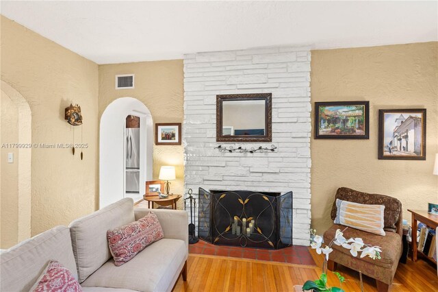 425 Cadagua Ave, Coral Gables, FL 33146 - living room with a textured wall, wood finished floors, arched walkways, and a fireplace