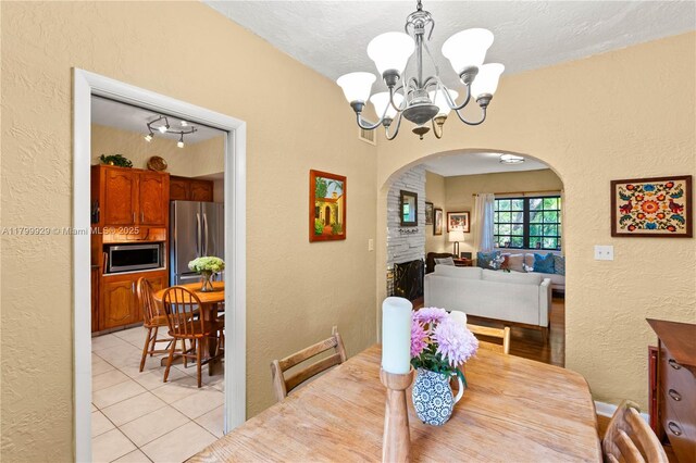 425 Cadagua Ave, Coral Gables, FL 33146 - dining space with a textured wall, arched walkways, a chandelier, light tile patterned flooring, and a textured ceiling