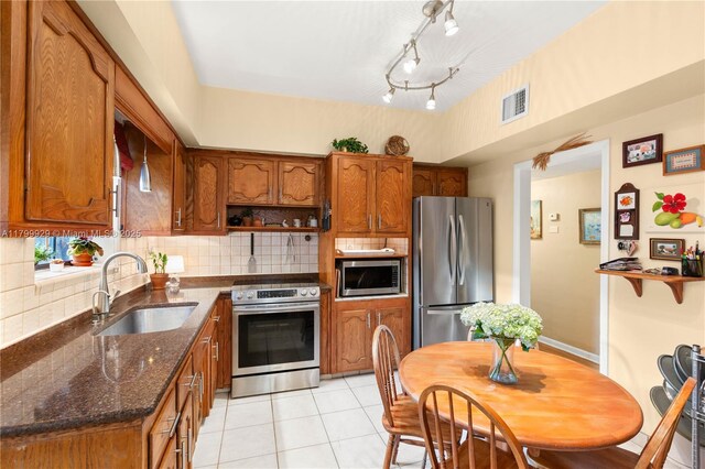 425 Cadagua Ave, Coral Gables, FL 33146 - kitchen featuring appliances with stainless steel finishes, a sink, brown cabinetry, and backsplash