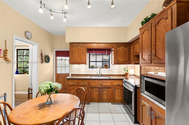 425 Cadagua Ave, Coral Gables, FL 33146 - kitchen with stainless steel appliances, brown cabinetry, a sink, and decorative backsplash