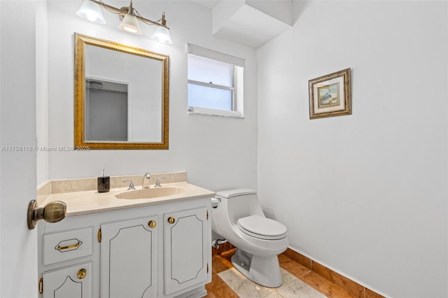 bathroom with toilet, vanity, tile patterned floors, and baseboards