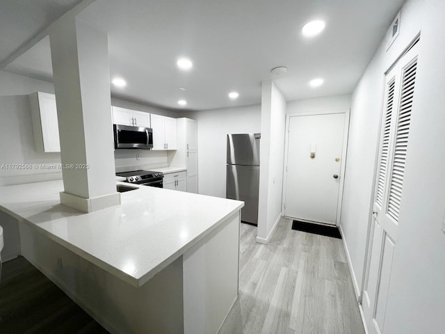 7950 W Mcnab Rd Unit 222, Tamarac, FL 33321 - kitchen featuring appliances with stainless steel finishes, recessed lighting, white cabinets, light wood finished floors, and light countertops