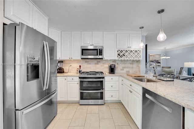 121 Tacoma Ln, Palm Beach Shores, FL 33404 - kitchen with appliances with stainless steel finishes, a sink, white cabinets, tasteful backsplash, and pendant lighting