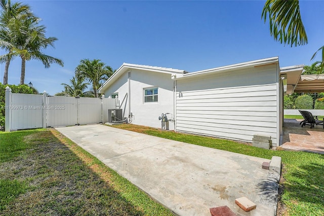 121 Tacoma Ln, Palm Beach Shores, FL 33404 - view of side of home with a gate, cooling unit, a patio area, and stucco siding