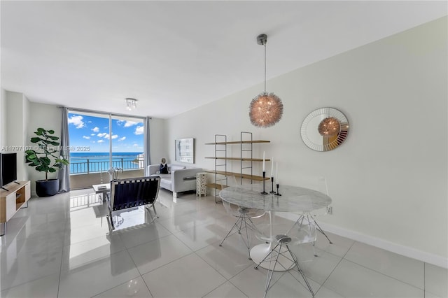 dining space featuring a wall of windows, baseboards, an office area, light tile patterned floors, and a water view