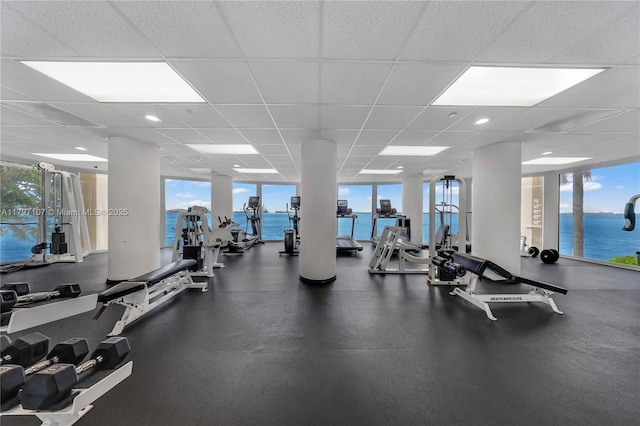 exercise room featuring plenty of natural light, a water view, and a drop ceiling
