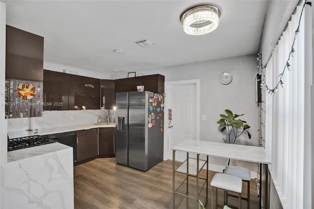 1155 Hayes St, Hollywood, FL 33019 - kitchen with stainless steel refrigerator with ice dispenser, dark brown cabinets, light wood-style flooring, and light stone counters