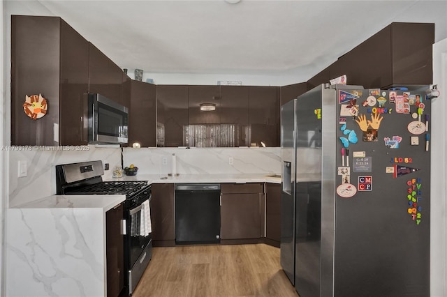 1155 Hayes St, Hollywood, FL 33019 - kitchen with appliances with stainless steel finishes, light wood-style flooring, backsplash, dark brown cabinets, and light stone counters