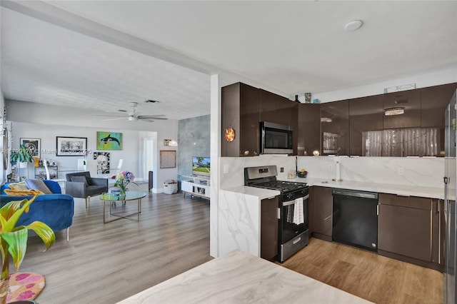 1155 Hayes St, Hollywood, FL 33019 - kitchen with stainless steel appliances, open floor plan, dark brown cabinets, light wood-style floors, and decorative backsplash