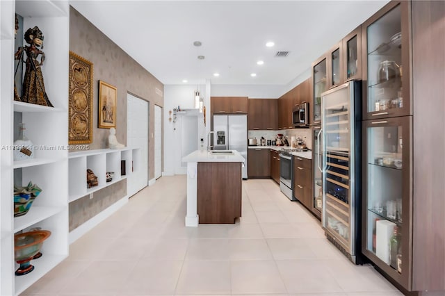 8301 NW 41st St Unit B-305, Doral, FL 33166 - kitchen with appliances with stainless steel finishes, light countertops, a kitchen island with sink, hanging light fixtures, and glass insert cabinets
