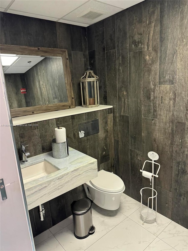 3851 NW 124th Ave, Coral Springs, FL 33065 - bathroom with toilet, marble finish floors, a sink, and wood walls