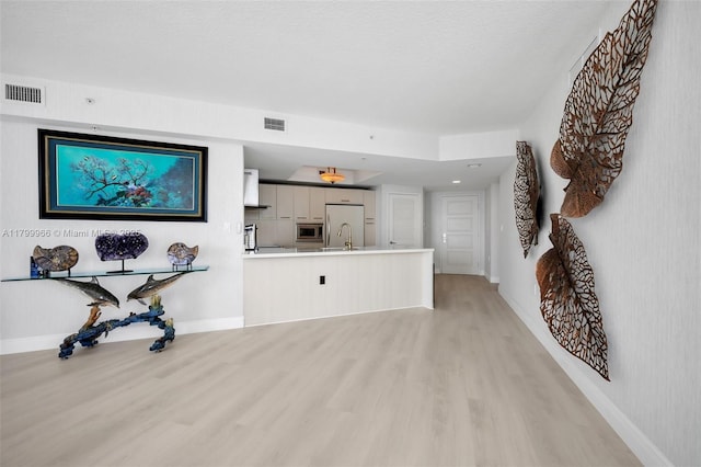 unfurnished living room featuring light wood-style flooring, a sink, and baseboards