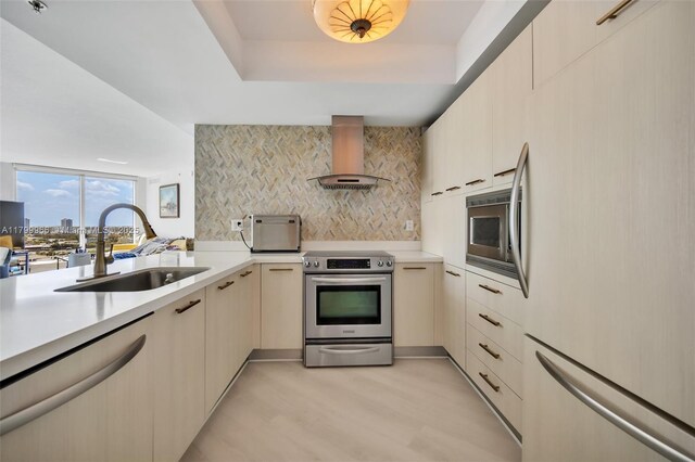 kitchen with appliances with stainless steel finishes, exhaust hood, a sink, backsplash, and light countertops