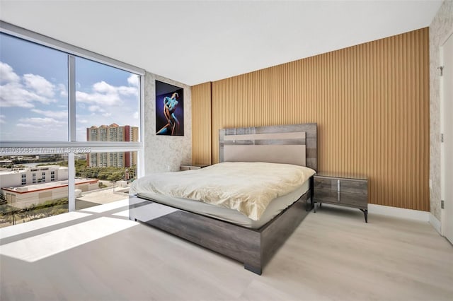 bedroom featuring wood finished floors, a view of city, and expansive windows