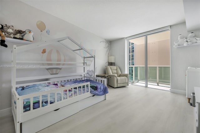 bedroom featuring access to outside, wood finished floors, and floor to ceiling windows