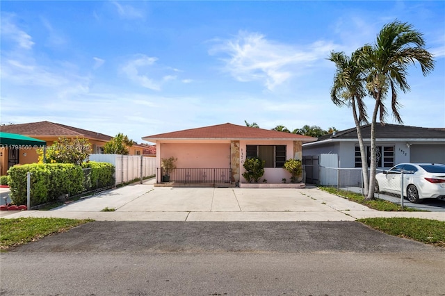 ranch-style home featuring stucco siding, fence, driveway, and a gate