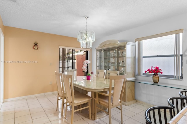 dining space featuring a chandelier, tile patterned floors, and a textured ceiling