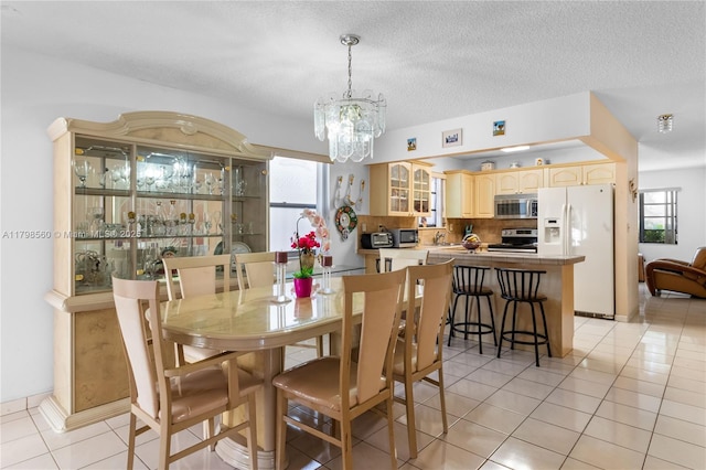 dining room with a chandelier, light tile patterned floors, and a textured ceiling