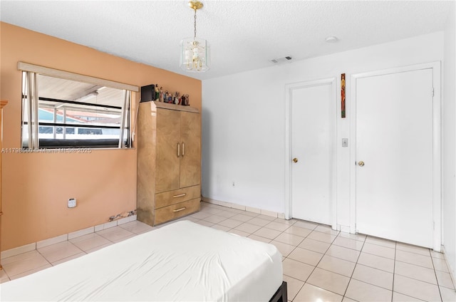 bedroom featuring light tile patterned flooring, a textured ceiling, and a chandelier