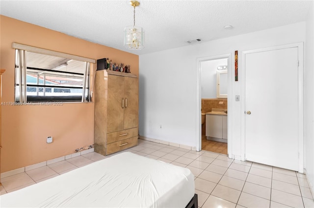 bedroom featuring light tile patterned floors, a chandelier, a textured ceiling, baseboards, and connected bathroom
