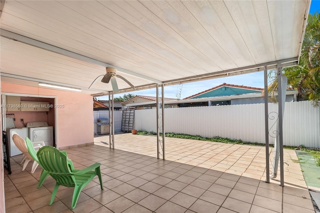 view of patio / terrace with washer and clothes dryer, fence, and ceiling fan
