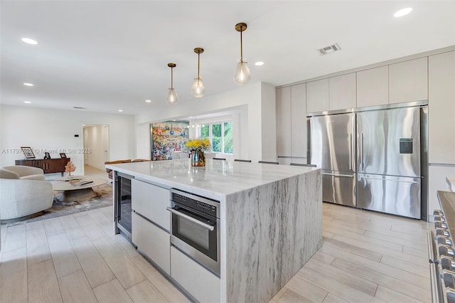 515 NE 115th St, Biscayne Park, FL 33161 - kitchen with appliances with stainless steel finishes, beverage cooler, modern cabinets, light wood finished floors, and light stone counters