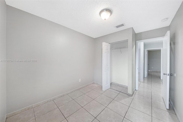 19231 SW 121st Ave, Miami, FL 33177 - unfurnished bedroom with a textured ceiling, a closet, light tile patterned floors, and baseboards
