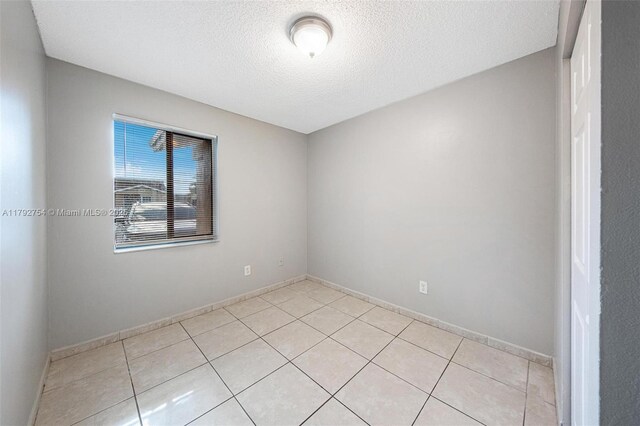 19231 SW 121st Ave, Miami, FL 33177 - spare room with light tile patterned flooring, a textured ceiling, and baseboards