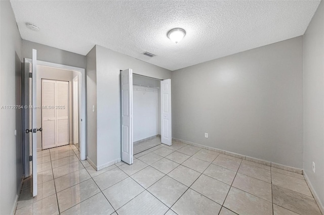 19231 SW 121st Ave, Miami, FL 33177 - unfurnished bedroom with light tile patterned flooring, a textured ceiling, baseboards, and a closet
