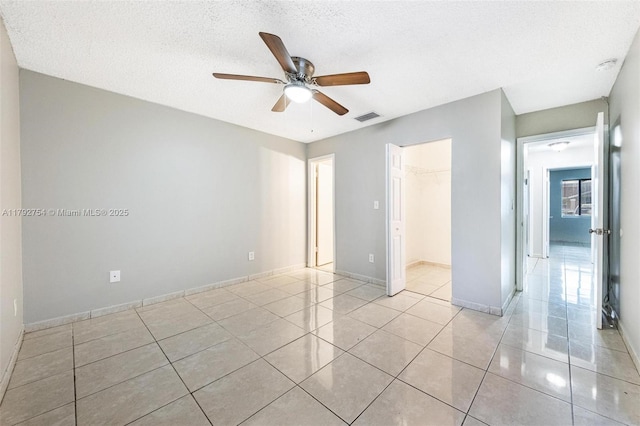 19231 SW 121st Ave, Miami, FL 33177 - unfurnished bedroom with light tile patterned floors, baseboards, a walk in closet, a closet, and a textured ceiling