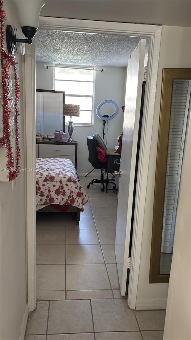 801 NW 47th Ave Unit 503W, Miami, FL 33126 - corridor featuring light tile patterned floors, a desk, a textured ceiling, and baseboards