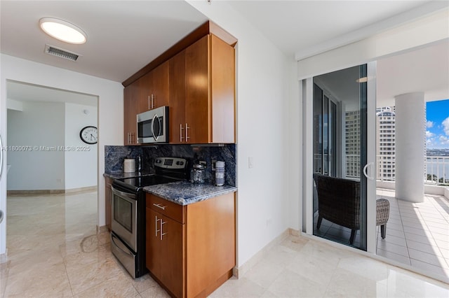 kitchen with stainless steel appliances, decorative backsplash, baseboards, dark stone counters, and light tile patterned floors