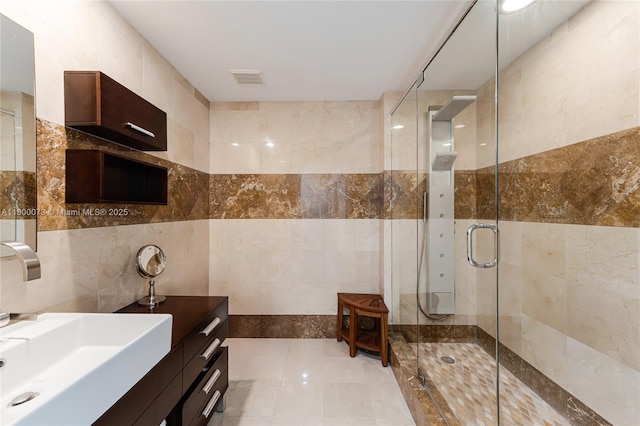 bathroom with tile walls, a shower stall, and vanity