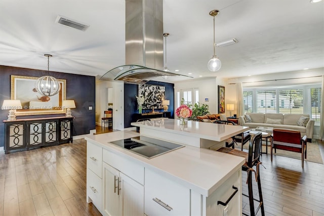 kitchen with black electric stovetop, open floor plan, island exhaust hood, and light wood-style floors