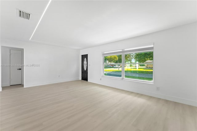 spare room featuring light wood-type flooring and baseboards