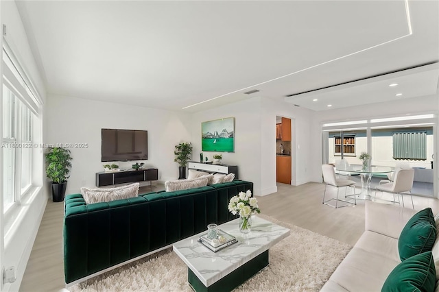 living room with light wood-style floors, recessed lighting, and baseboards